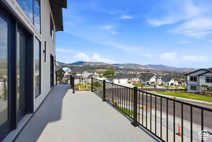 Expansive balcony featuring a textured surface, black metal railing, and direct access to interior spaces