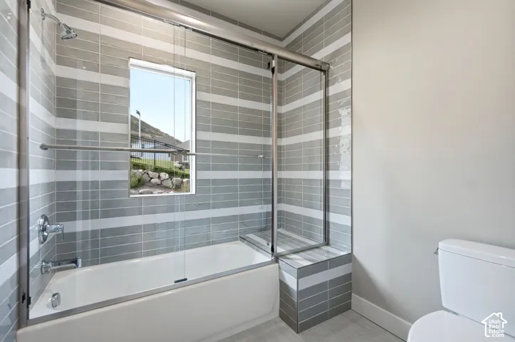 Large bath area. Bathtub features tile to the ceiling, glass sliding door and you will love the added bench.