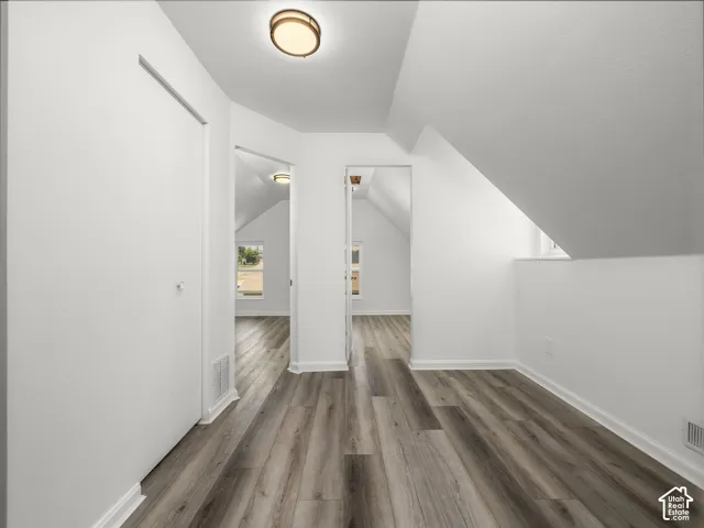 Hallway featuring wood-finish flooring, white walls, and bright overhead lighting