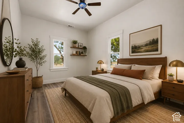Bright bedroom featuring wood-finish flooring, two large windows, a ceiling fan, and floating wall shelves