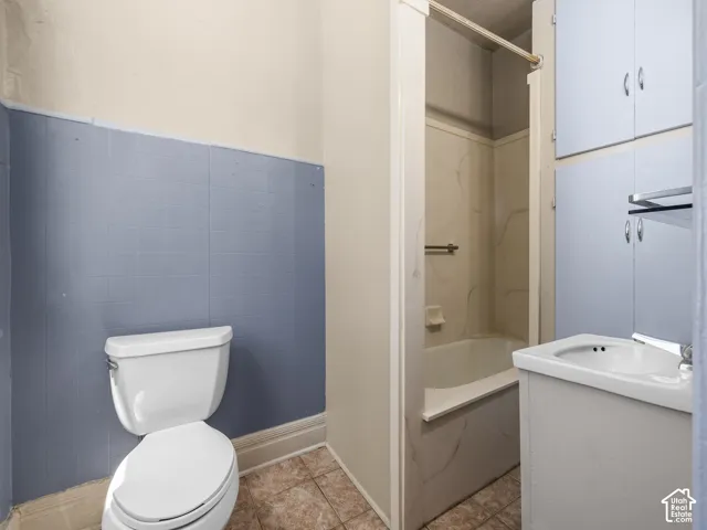 Bathroom featuring a white toilet, tile flooring, and light blue wall tiling