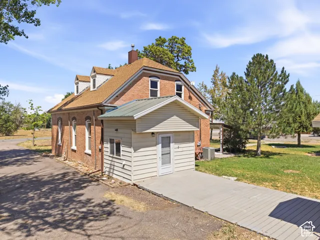 Brick exterior featuring a wood-shingle roof, multiple dormers, and an attached extension with siding and a metal roof