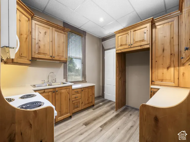 Kitchen featuring wood cabinetry, laminate countertops, wood-finish flooring, a double basin sink, and a built-in range