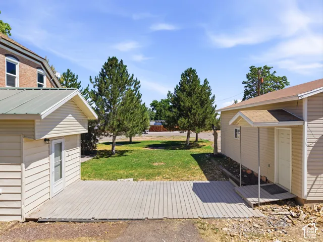Expansive exterior space featuring a wooden deck, a separate structure with a metal roof, and another structure with an asphalt shingle roof