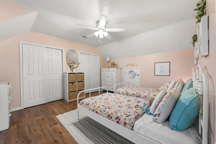 Bedroom featuring lofted ceiling, multiple closets, dark wood-style floors, and ceiling fan
