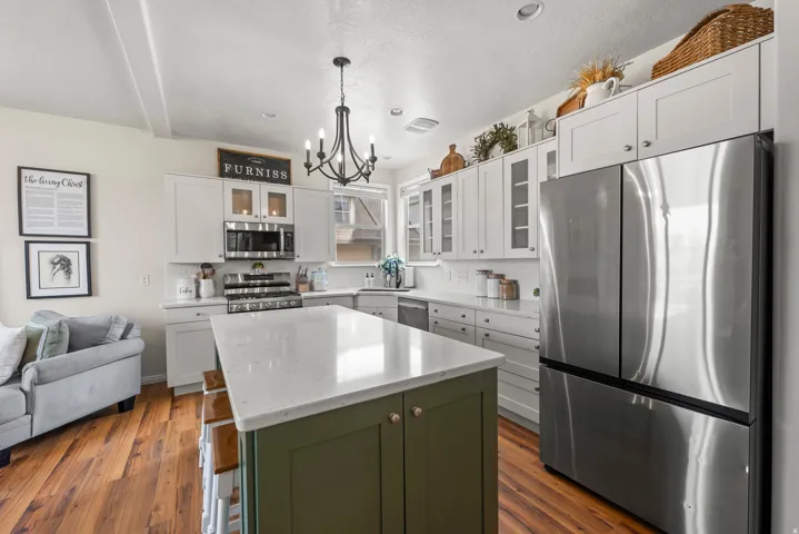 Kitchen featuring stainless steel appliances, a kitchen island, glass fronted cabinets, light stone countertops, and open floor plan