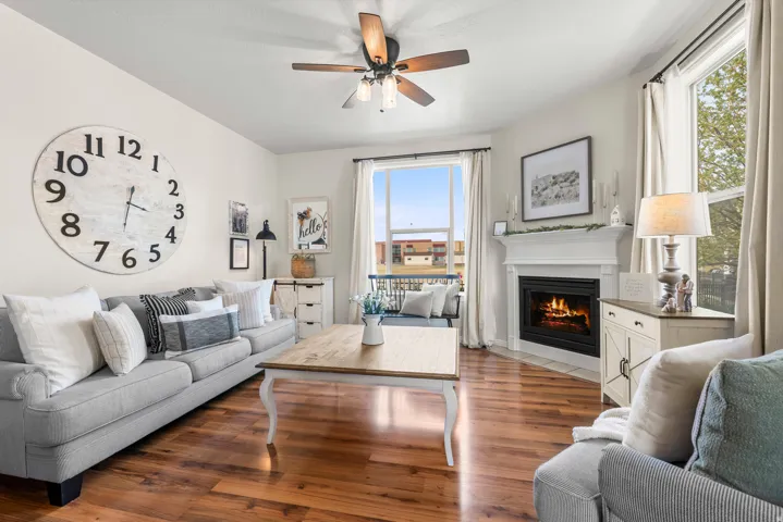 Living room with wood finished floors, a ceiling fan, and a fireplace with flush hearth