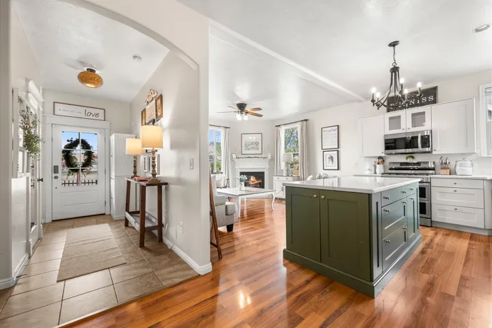 Kitchen with dual tone cabinets, stainless steel appliances, glass insert cabinets, a ceiling fan, and a kitchen island