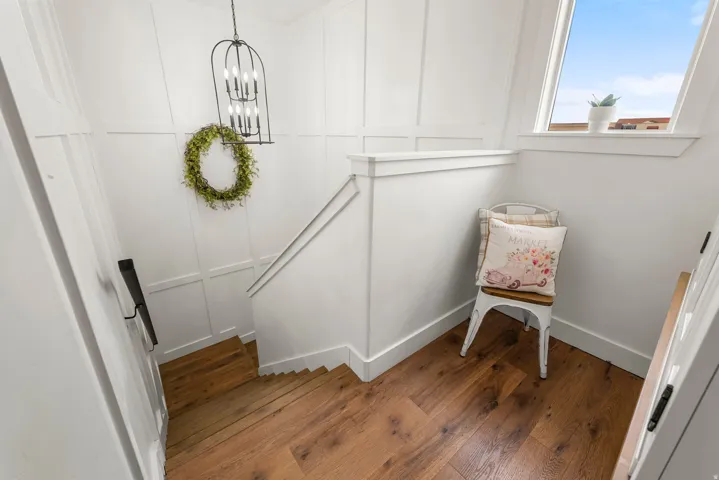 Stairs featuring a decorative wall, hardwood / wood-style flooring, and suspended lighting