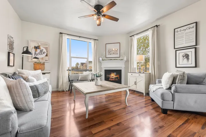 Living room with wood finished floors, plenty of natural light, a ceiling fan, and a glass covered fireplace