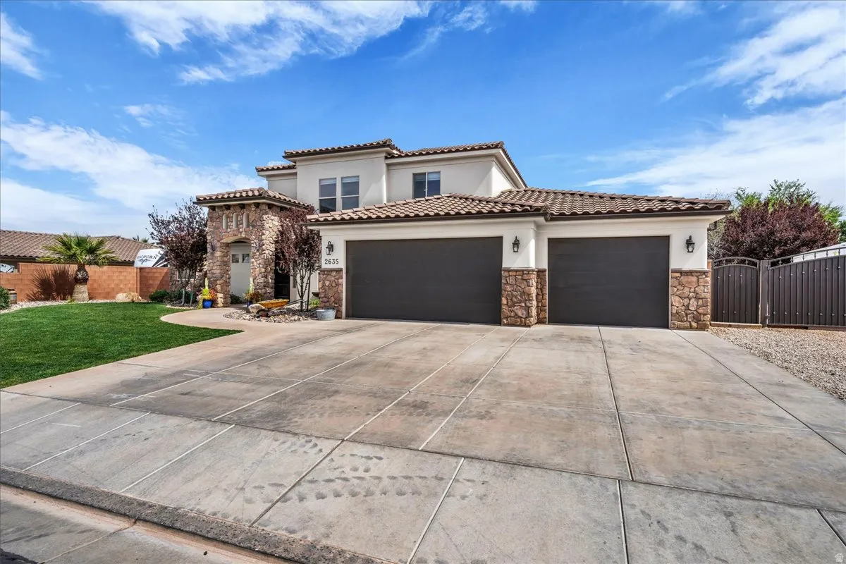 Mediterranean / spanish-style home with stone siding, a garage, stucco siding, a gate, and driveway
