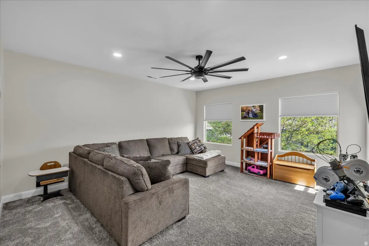 Carpeted living area featuring a ceiling fan and recessed lighting