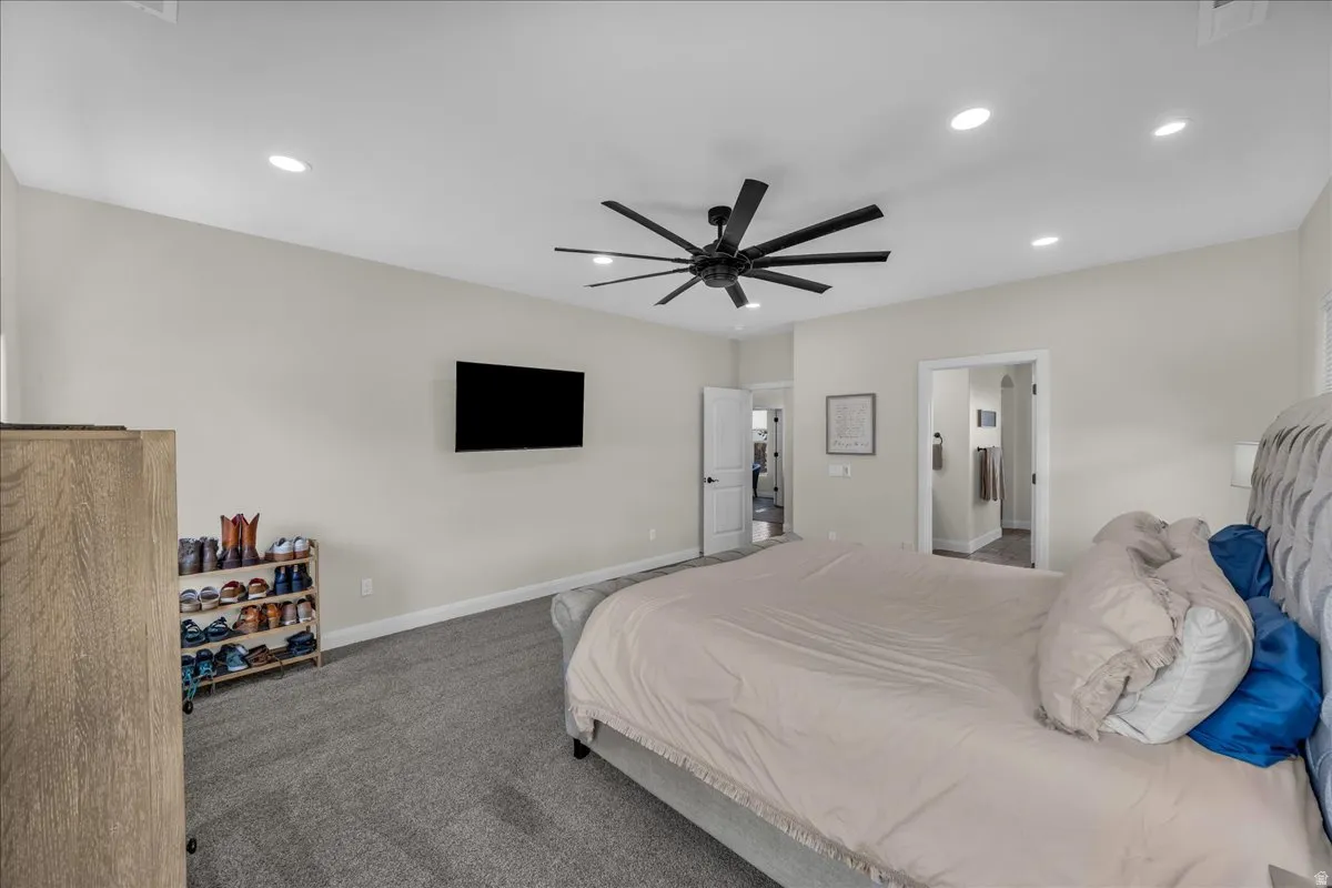 Bedroom featuring dark carpet, a ceiling fan, recessed lighting, and ensuite bathroom