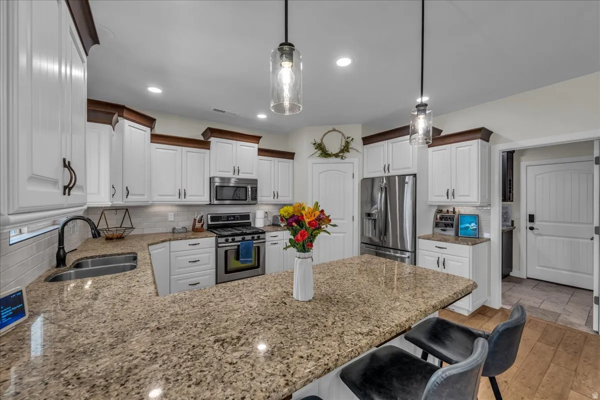 Kitchen featuring a peninsula, stainless steel appliances, a kitchen bar, and decorative backsplash