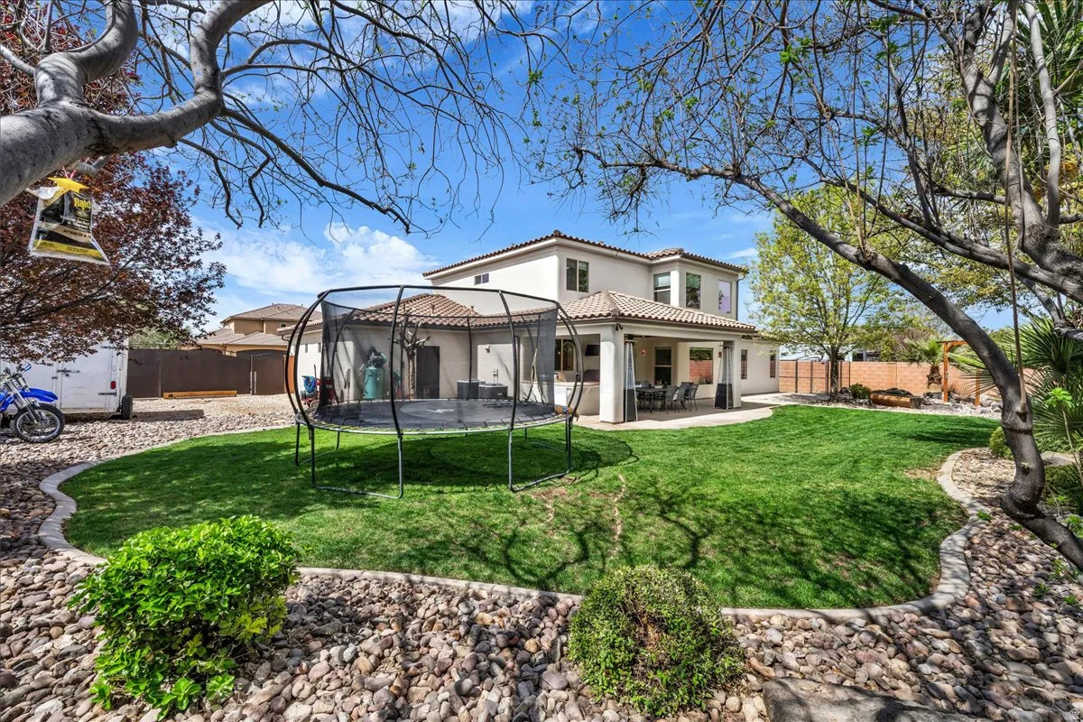 Back of property with a patio area, stucco siding, a fenced backyard, a tile roof, and a trampoline