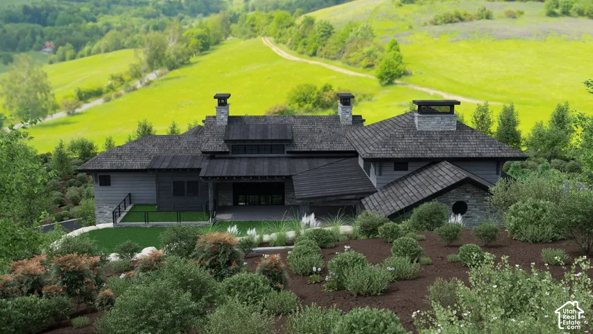 Stone and wood-sided exterior featuring multiple chimneys, a dark shingle roof, and an integrated covered patio