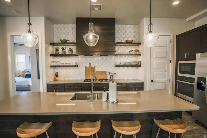 Kitchen with decorative backsplash, a breakfast bar area, pendant lighting, and a textured ceiling