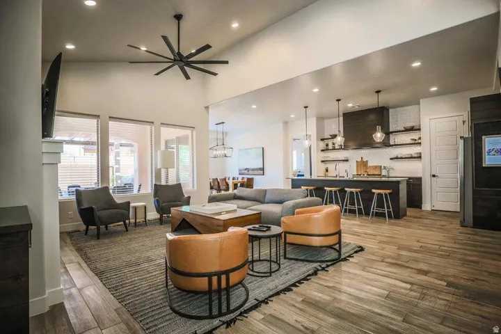 Living room featuring light wood-style flooring, wet bar, recessed lighting, a high ceiling, and ceiling fan