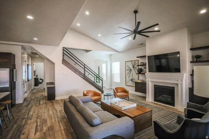 Living room featuring a glass covered fireplace, wood finished floors, ceiling fan, arched walkways, and recessed lighting