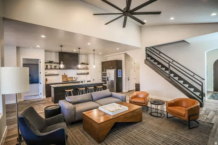 Living area featuring light wood finished floors, recessed lighting, ceiling fan, a high ceiling, and arched walkways
