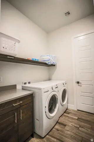 Laundry room with dark wood-style flooring, cabinet space, and washing machine and dryer