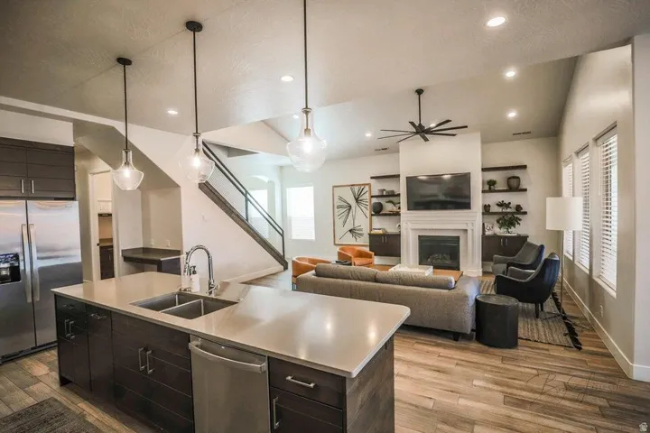 Kitchen with stainless steel appliances, a kitchen island with sink, light wood-style floors, dark wood finish cabinets, and vaulted ceiling