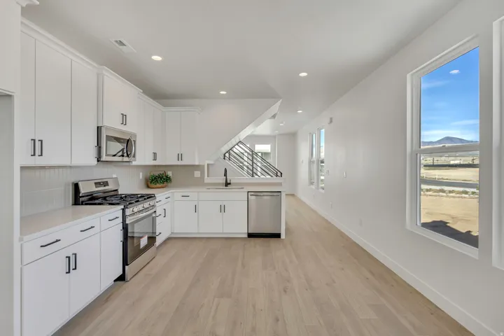 Kitchen with stainless steel appliances, light countertops, decorative backsplash, light wood-type flooring, and recessed lighting