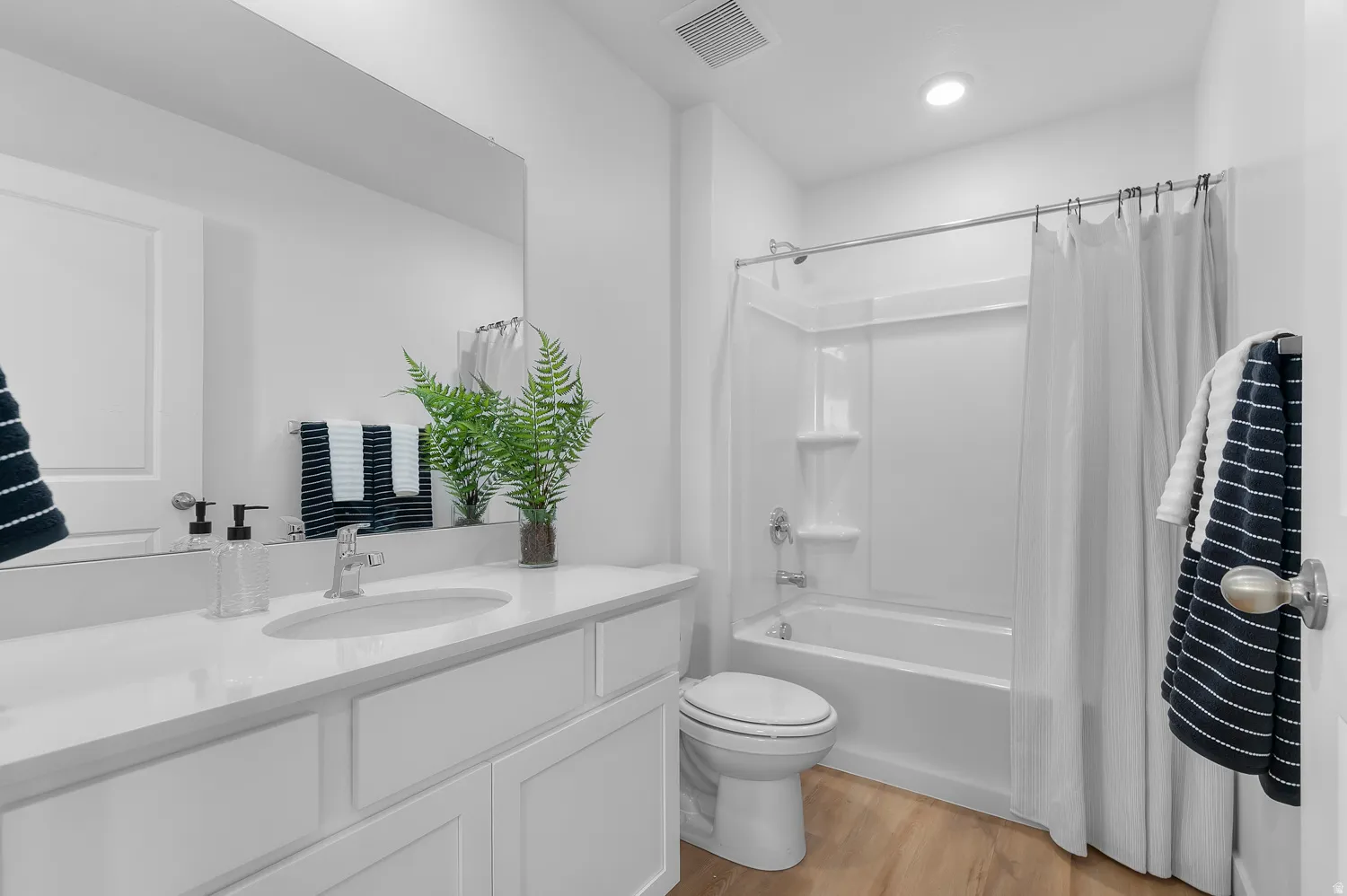 Full bath with vanity, light wood-type flooring, and shower / tub combo