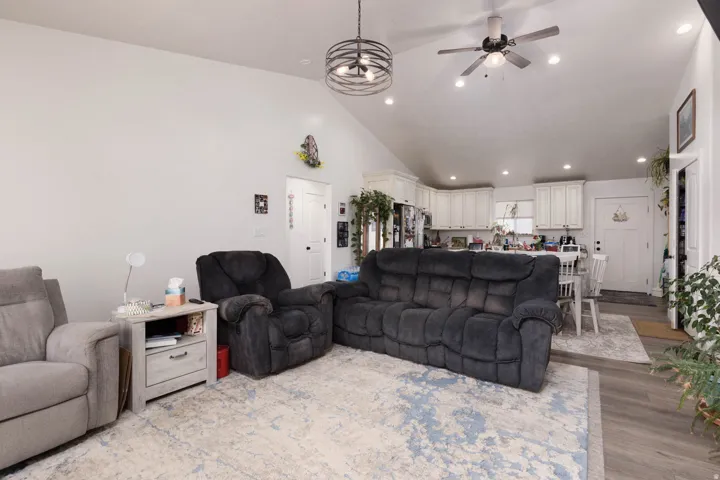 Living area featuring lofted ceiling, a ceiling fan, light wood-style floors, and recessed lighting