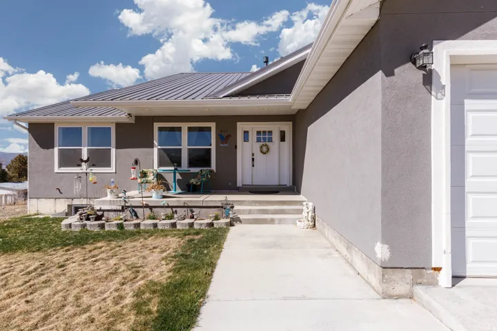 Property entrance featuring stucco siding, a lawn, and a metal roof