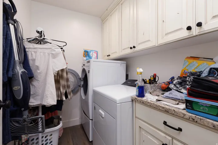 Laundry room with washer and clothes dryer, cabinet space, and dark wood-type flooring