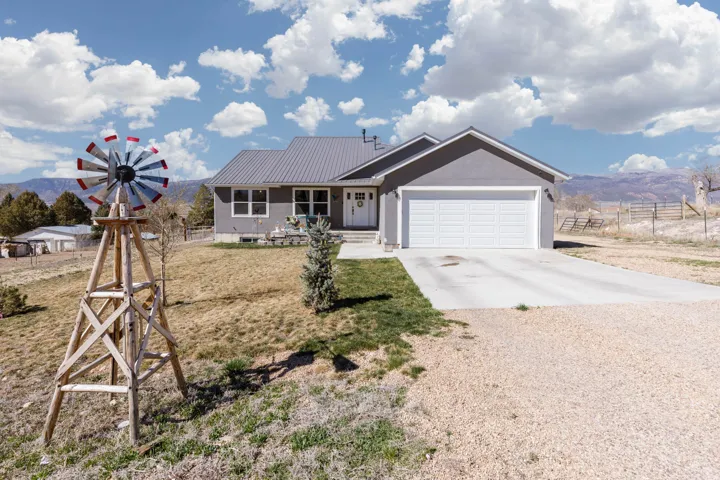 Single story home featuring concrete driveway, a mountain view, covered porch, a metal roof, and an attached garage