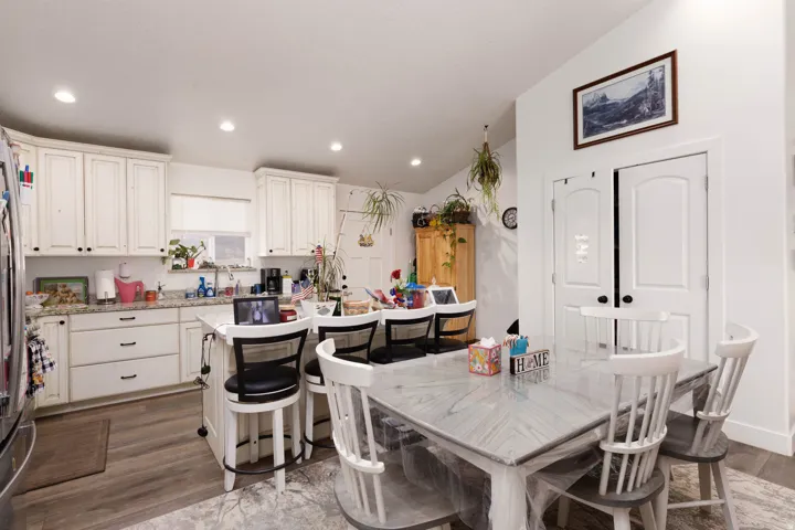 Kitchen featuring a breakfast bar area, lofted ceiling, a center island with sink, white cabinetry, and dark wood-type flooring
