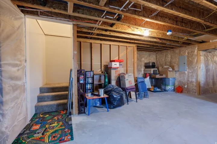 Unfinished below grade area with electric panel and stairway