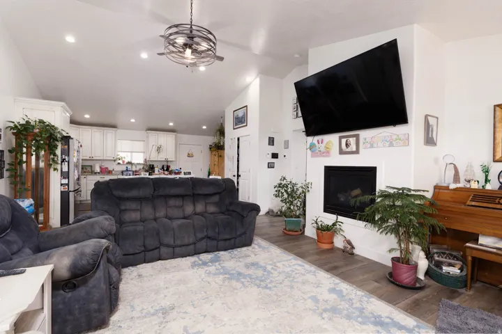 Living area with lofted ceiling, a fireplace, wood finished floors, and recessed lighting