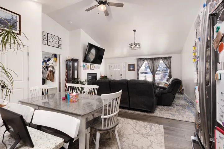 Dining space featuring vaulted ceiling, wood finished floors, ceiling fan, and a glass covered fireplace