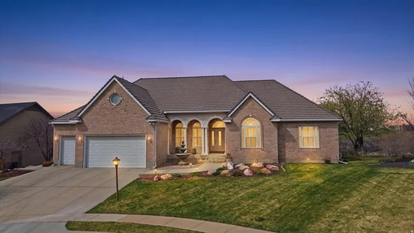 View of front of house with brick siding, an attached garage, a front lawn, and concrete driveway