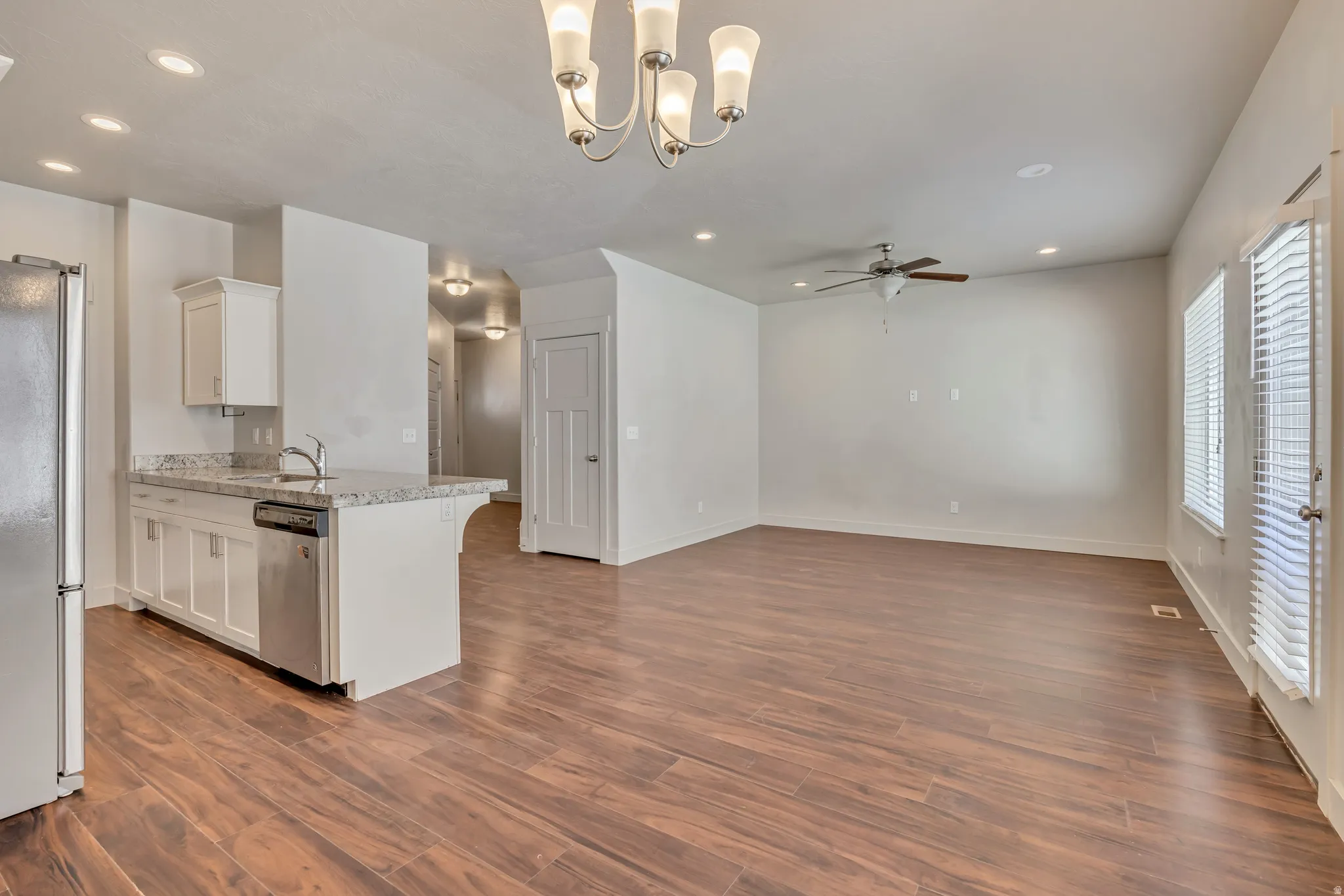 Kitchen featuring white cabinetry, stainless steel appliances, open floor plan, a chandelier, and a peninsula