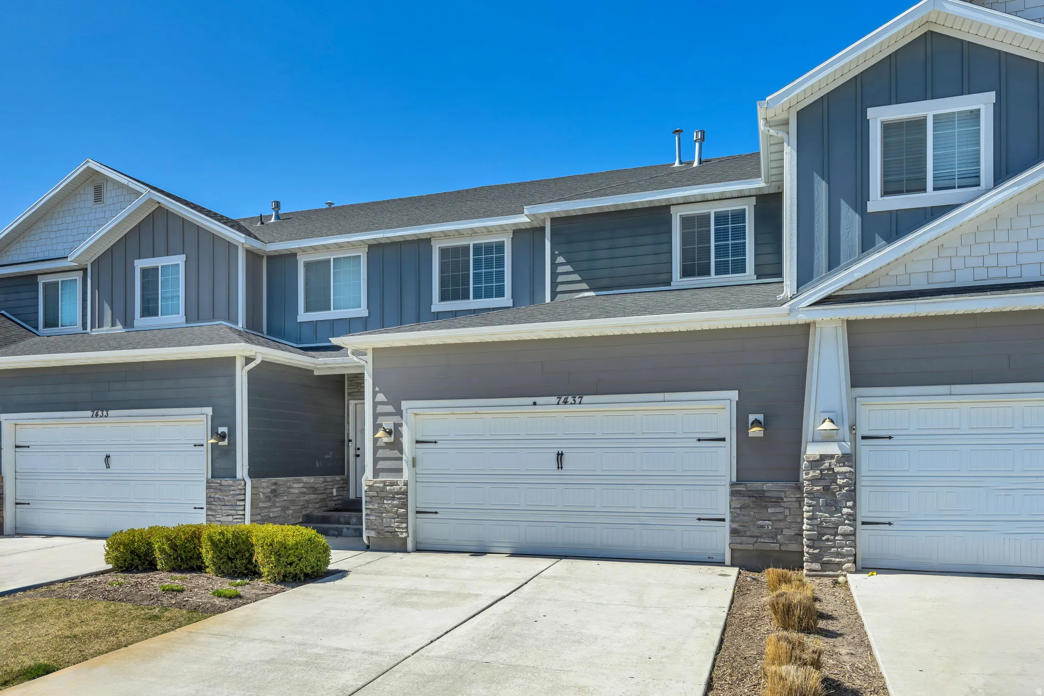 Craftsman house featuring board and batten siding, stone siding, concrete driveway, a garage, and roof with shingles
