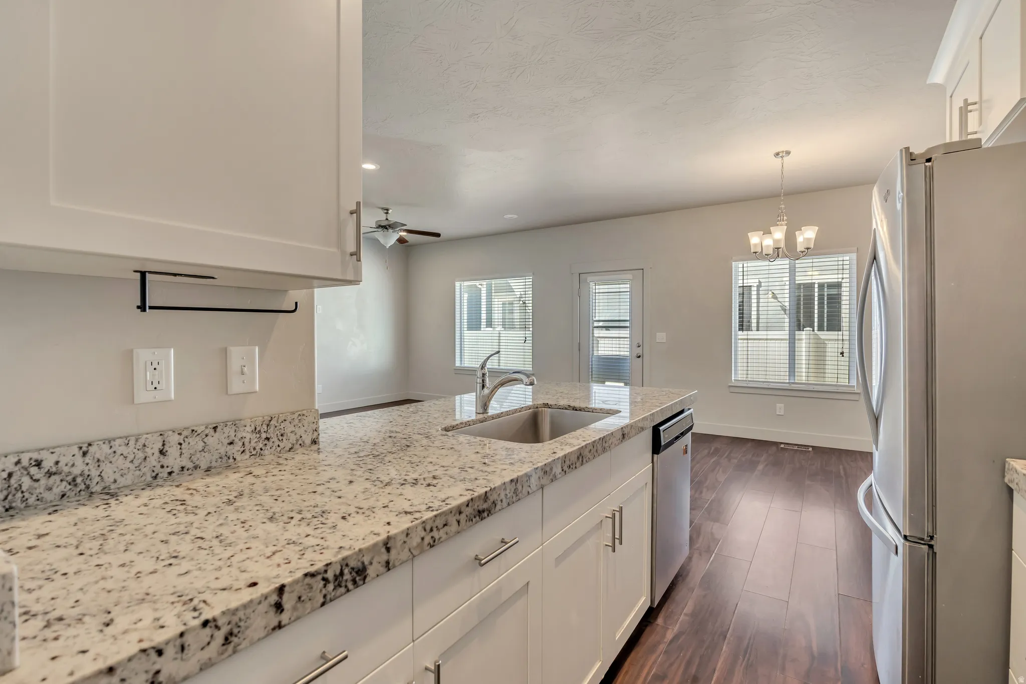 Kitchen featuring white cabinetry, stainless steel appliances, light stone counters, a peninsula, and a ceiling fan