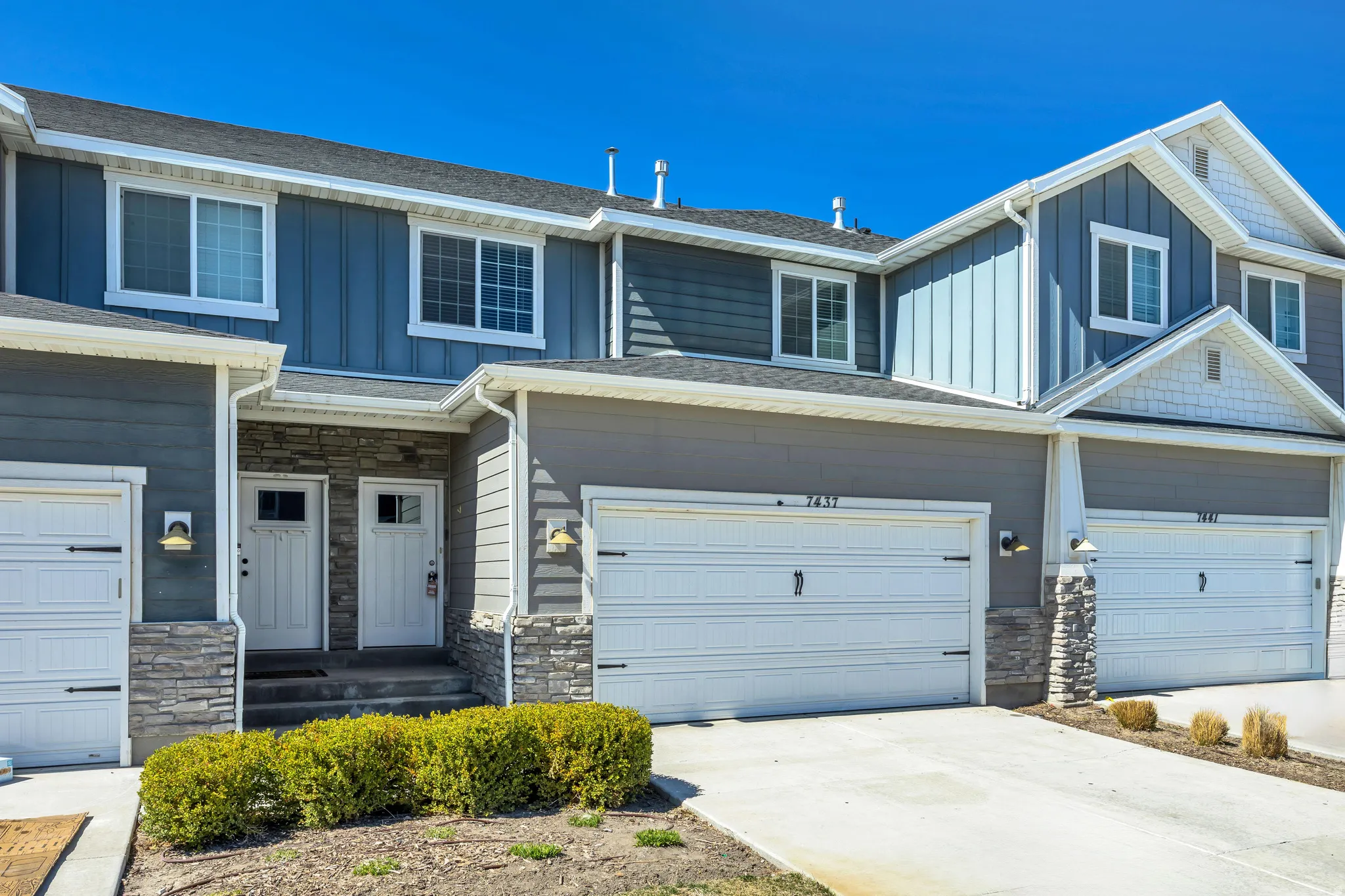 Craftsman-style house featuring stone siding, board and batten siding, concrete driveway, a garage, and a shingled roof