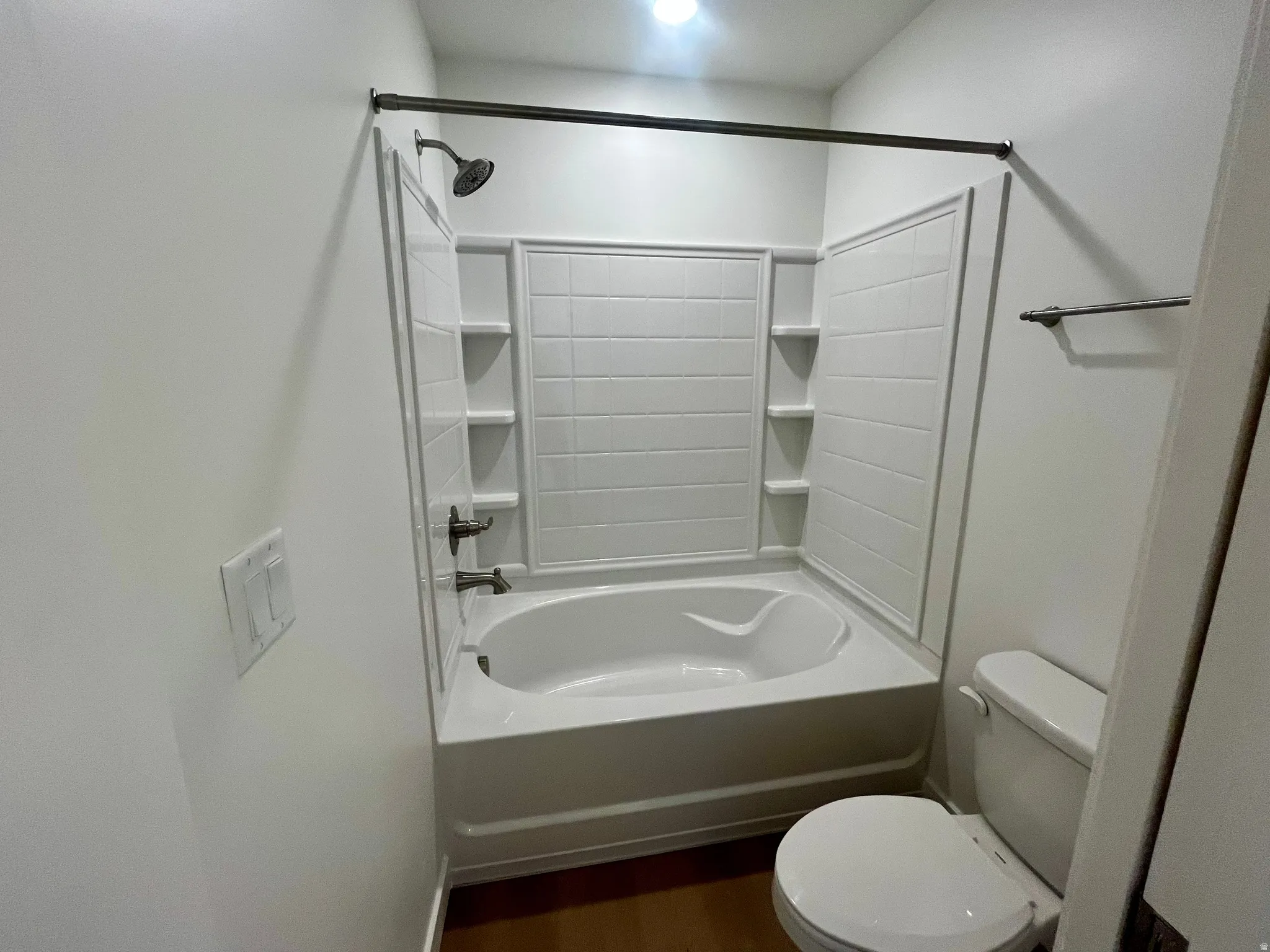 Bathroom with dark wood-style floors and bathing tub / shower combination