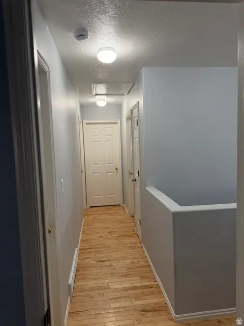 Hall featuring a textured ceiling and light wood-type flooring