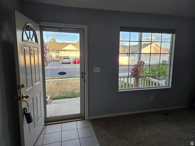 Entrance foyer with plenty of natural light, light tile patterned floors, and light carpet