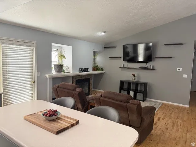 Living area featuring light wood-style floors and a glass covered fireplace