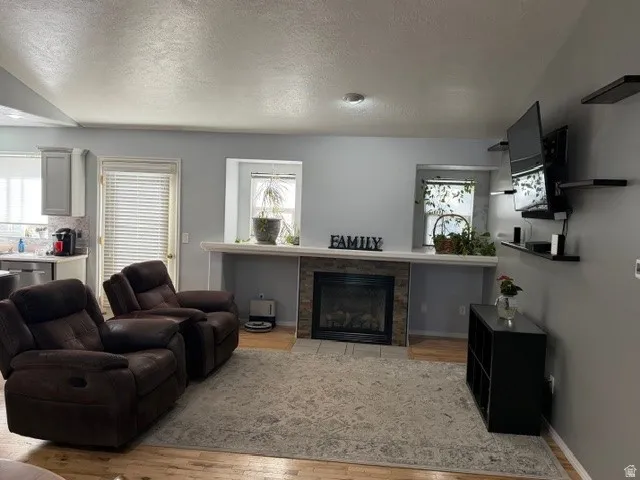 Living area featuring a textured ceiling, wood finished floors, and a fireplace
