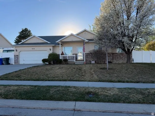 Ranch-style home with a garage, driveway, stucco siding, and covered porch