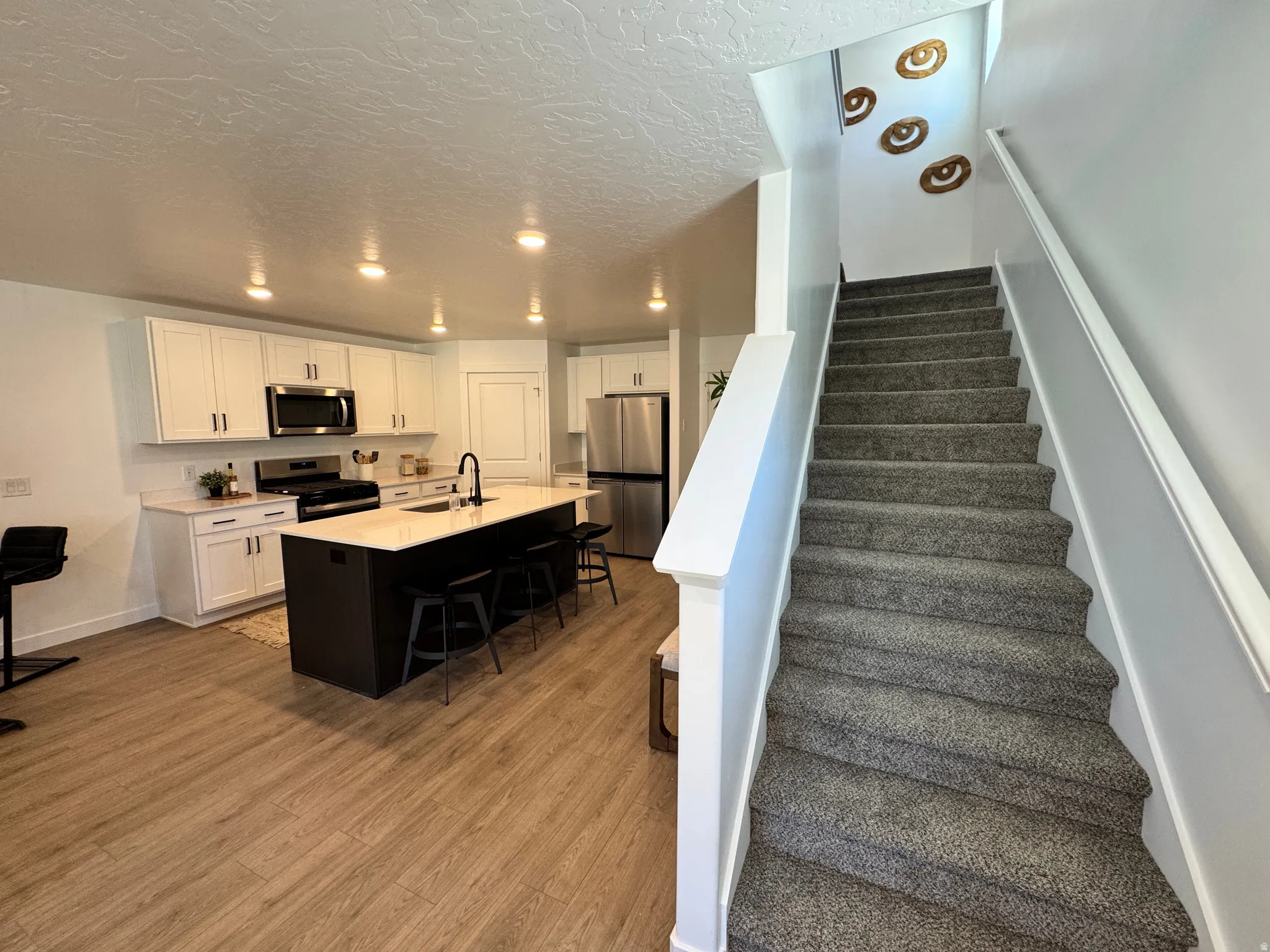 Modern kitchen featuring white cabinetry, stainless steel appliances, a center island with seating, and wood-finish flooring