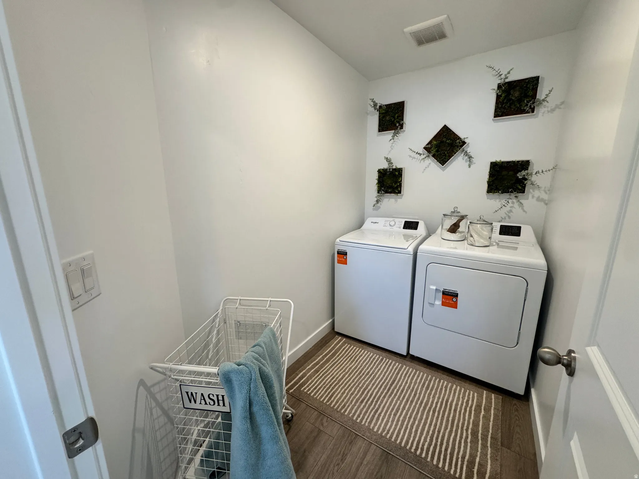 Dedicated laundry area featuring wood-finish flooring, white walls, and an overhead ventilation system