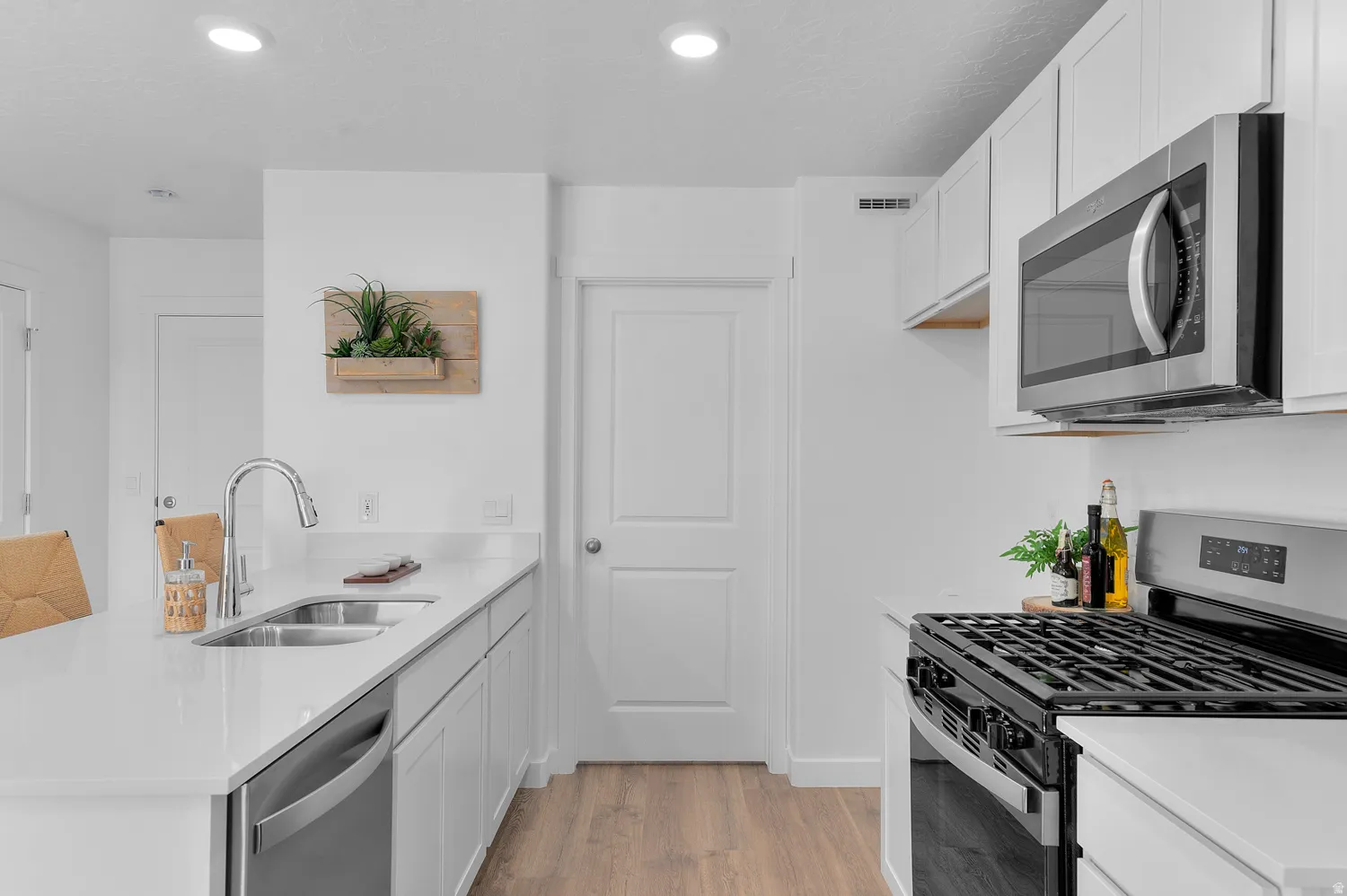 Kitchen with stainless steel appliances, white cabinets, a peninsula, light stone countertops, and recessed lighting